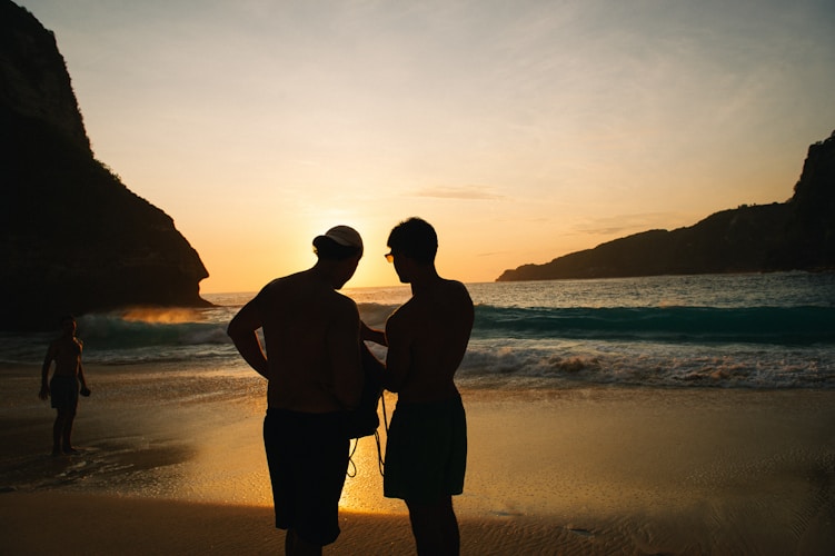A couple of people standing on top of a beach