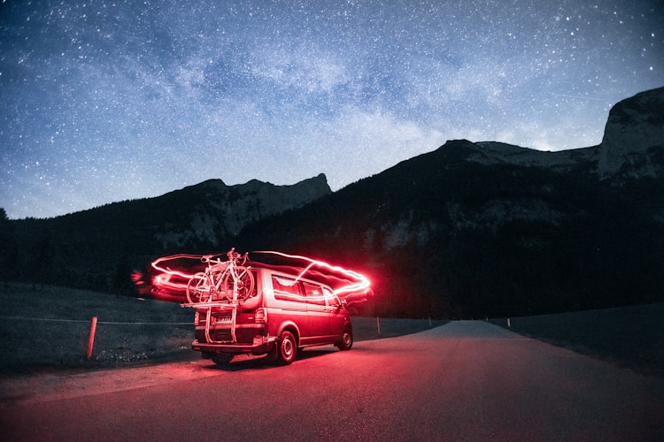 A car parked on the side of a road under a night sky